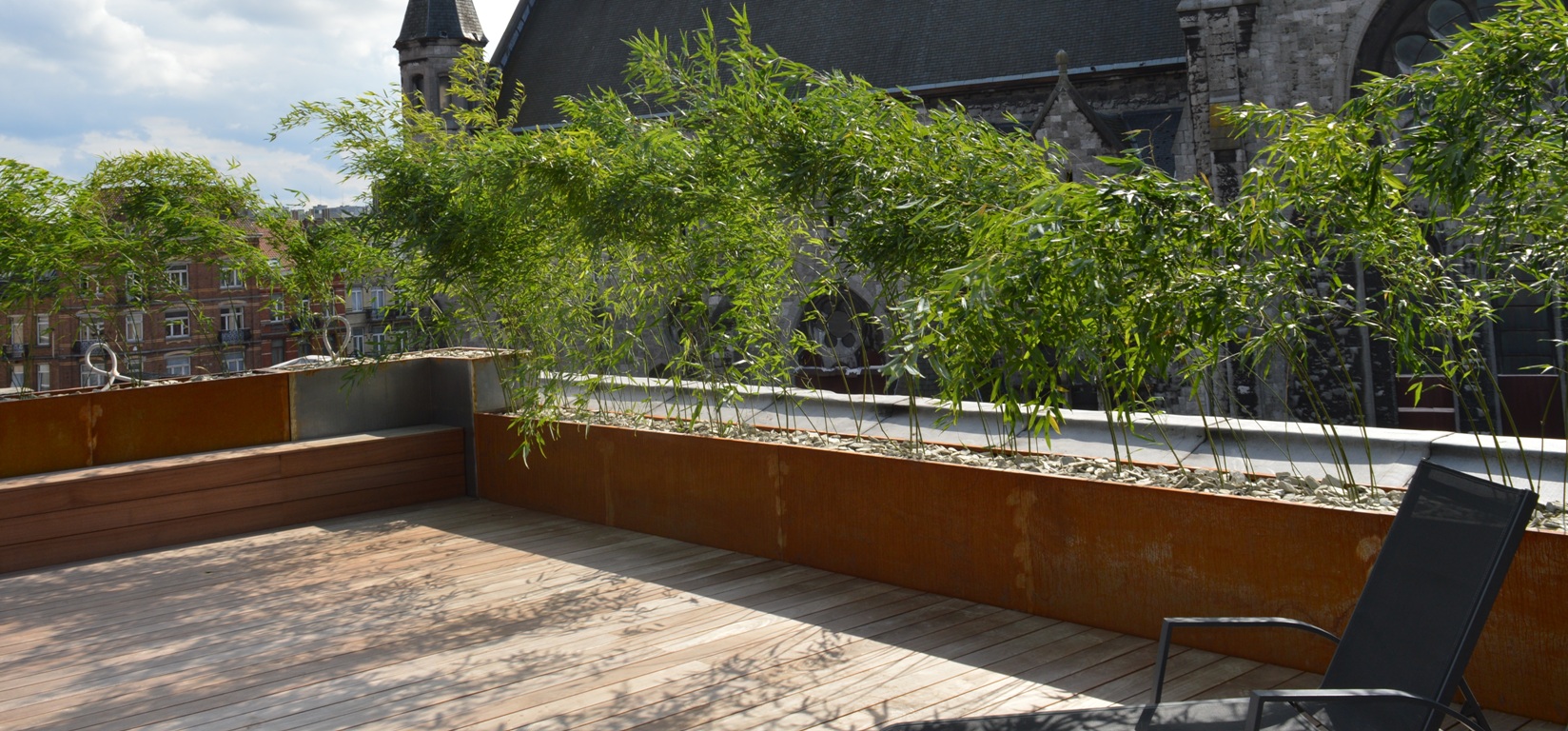 Bering corten 150x50x60, fini brut, pose en ligne, bacs boulonnés sur 2 hauteurs isolant le toit-terrasse de la place de l'église